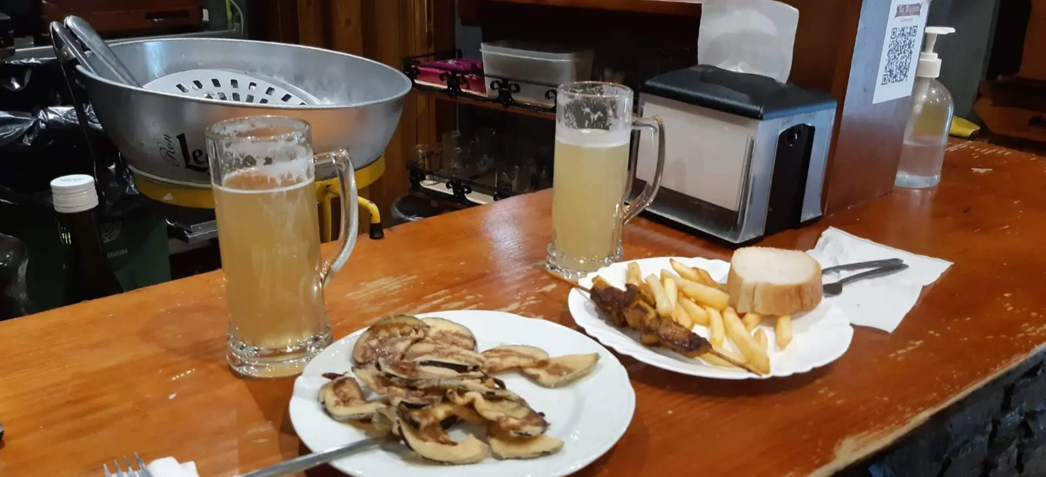 Tapas en el Bar La Riviera de Granada, con una ración de berenjenas con miel y una brocheta con patatas fritas, acompañadas de dos cañas bien frías.