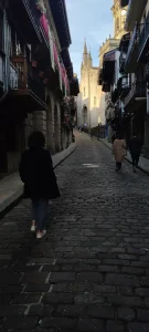 Gente caminando por una calle empedrada del casco antiguo de Hondarribia hacia la iglesia.