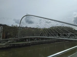Vista lateral del Puente Zubizuri en Bilbao con personas cruzando